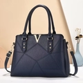 Macro detail of navy tote bag featuring pebble grain texture and golden V hardware - Blue