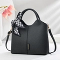 Elegante borsa a mano in tessuto nero con foulard in seta e logo su sfondo bianco - Nero