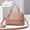 Close-up of pink lychee grain leather saddle bag with gold hardware and top handle detail - Pink