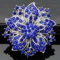 Macro detail of silver floral brooch with dark blue rhinestones on black reflective base - Royal Blue