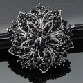 Close-up of elegant silver flower brooch with black rhinestones and layered petals design - Black