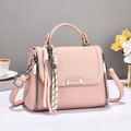 Close-up of pink litchi grain leather bag with silver metal bar and tassel charm - Pink