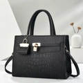 Detail of black textured leather bag with crocodile pattern and golden padlock hardware - Black