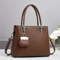 Detail einer dunkelbraunen Handtasche aus Kieselleder mit silbernen Metallakzenten - Kaffeebraun