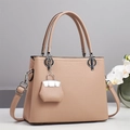 Detail of warm apricot lychee grain leather handbag with silver hardware and mini charm - Pink