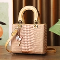Brown crocodile embossed handbag with pearl sea charm on a warm textured wooden surface - Ginger Yellow