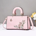 Gros plan détaillé du sac en cuir rose avec broderies de pivoines et finitions dorées - Rose