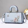 Detailed embroidery of floral and butterfly patterns on a light blue handbag - Blue