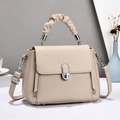 Close-up of beige lychee leather bag featuring a unique ruched handle and silver oval lock - Light Khaki