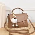 Borsa a tracolla marrone trama litchi con ciondolo di peluche su tavolo in legno - Cachi
