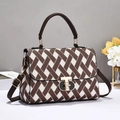 Detailed close-up of brown geometric jacquard weave texture and golden twist lock on handbag - Coffee