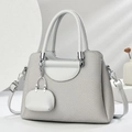Close-up of light grey tweed handbag with leather trim and matching mini charm pendant - Gray