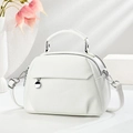Minimalist white leather handbag with dual zippers and silver pendant in a lifestyle setting - White