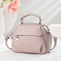 Elegant dusty pink crossbody bag with top handle and silver pendant on a white background - Pink