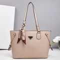 Dettaglio della borsa tote in pelle beige con logo a triangolo dorato e sciarpa di seta decorativa - Cachi