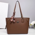 Dettaglio della borsa tote in pelle martellata marrone con foulard e logo - caffè
