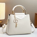 White woven texture handbag with triangle flap and crystal C charm in a lifestyle setting - Off White