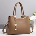 Détail du sac à main en cuir grainé marron avec finitions dorées et lettrage gravé - Kaki