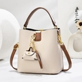 Détail du sac seau beige à motif litchi avec anses brunes et finitions dorées - Beige