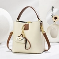 Close-up of cream white lychee texture bucket bag with brown handles and a mini pouch charm - Off-white