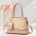 Elegant apricot woven leather handbag with circular handles and decorative mini bag charm - Light Khaki