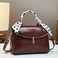 Sac à main marron à motif crocodile avec fermoir doré et foulard à pois sur la poignée - café