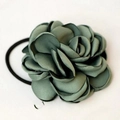 Elegant dark green camellia fabric hair tie with layered satin petals on a magazine - Green