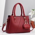Detail of burgundy lychee leather handbag with gold hardware and mini bag charm - Red