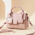 Pink patchwork handbag with scarf handle and woven texture detail in a soft scene - Pink