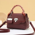 Detail der burgunderroten Lederhandtasche mit Deko-Schal am Griff und Silberverschluss - L 21 x B 10 x H 15 cm / Rot