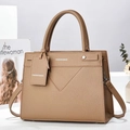 Detailed view of brown litchi grain leather handbag with adjustable strap and metal feet - Khaki