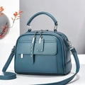 Macro detail of dark teal satchel bag showing premium leather texture and silver rivets - Blue