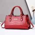 Detalle de bolso rojo efecto cocodrilo en charol con elegantes herrajes dorados - Rojo