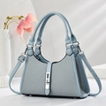 Hellblaue Umhängetasche mit Webstruktur und verstellbarem Riemen auf weißem Podest - L26cm B9cm H18cm / Blau