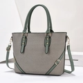 Dettaglio borsa in pelle verde e tela grigia con finiture metalliche dorate - Verde