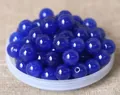 Macro shot of dark blue polished round beads with drill holes for DIY jewelry making - 8mm / Cyan Gold