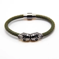 Nahaufnahme von olivgrünem Lederarmband mit zwei Totenköpfen und Magnetverschluss - Gun Black und Grün