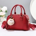 Elegant red pebbled leather handbag with cartoon cat charm and geometric woven strap - Red