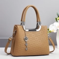 Détail de la texture gaufrée et du pendentif clé argenté sur le sac à main en cuir kaki - Khaki Foncé