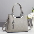 Gros plan d'un sac à main gris clair avec texture gaufrée et pendentif clé en argent - Gris