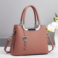 Sac à main rose gaufré élégant avec poignées argentées et breloque clé sur socle - Rose