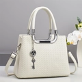 Close-up of white woven leather handbag texture with silver clover pendant detail - Off-white