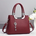 Detail of wine red tote bag with lychee texture and silver clover key pendant - Red