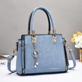 Sac à main bleu clair avec texture crocodile, détails dorés et charm de lapin - Bleu