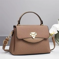 Detailed view of brown woven texture handbag featuring gold shield buckle and leather strap - Apricot