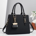 Elegant black textured tote bag with gold hardware and stylish charm on clean background - Black