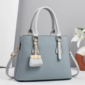 Elegant structured light blue handbag with lattice texture and mini bag charm accessory - Blue