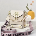 Beige crossbody bag with gold flamingo clasp and wide woven strap on a white stand - Off-white