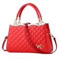 Détail du sac à main matelassé rouge avec nœud en métal doré et texture de couture - Rouge