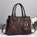Gros plan sur le sac en texture serpent marron avec détails dorés et mini pendentif - café